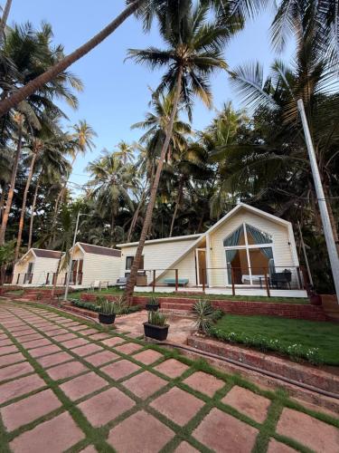 a white house with palm trees in the background at Sea Breeze, Guhagar in Guhagar