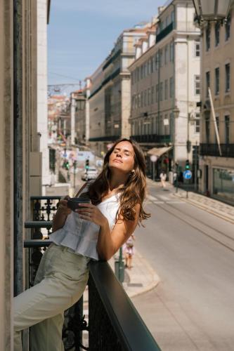 a woman leaning on a railing looking at a street at Pestana Rua Augusta Lisboa in Lisbon