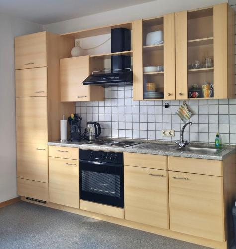 a kitchen with wooden cabinets and a stove top oven at Ferienwohnung für 1 bis 2 Personen in Fichtelberg