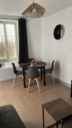 - un salon avec une table, des chaises et une horloge dans l'établissement Maison cosy près du circuit Nevers Magny-Cours, à Chaulgnes