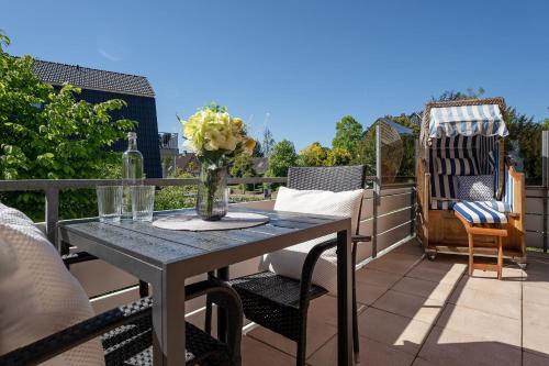 a patio table with chairs and a vase of flowers on a balcony at Ferienwohnung Jankar in Timmendorfer Strand