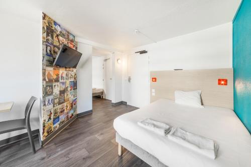 Cette chambre comprend un lit blanc et une télévision murale. dans l'établissement hotelF1 Cergy, à Cergy
