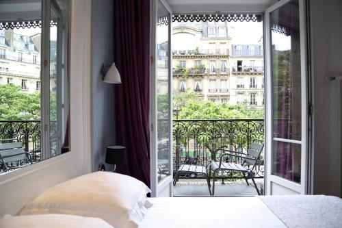 a bedroom with a bed and a balcony with a view at Stella Etoile in Paris