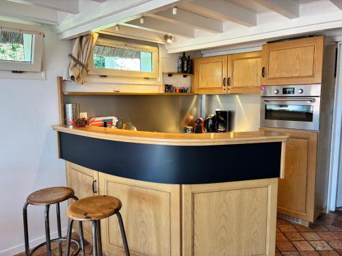- une cuisine avec un comptoir et deux tabourets dans l'établissement La petite chaumière sur le rivage, à Houlgate