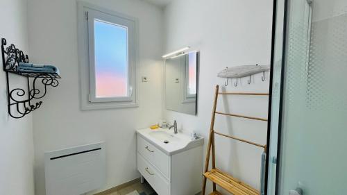 une salle de bain blanche avec un lavabo et un miroir dans l'établissement Les Alouettes centre ville et mer, à Saint-Jean-de-Monts