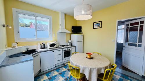une cuisine avec une table et une petite cuisine aux murs jaunes dans l'établissement Les Alouettes centre ville et mer, à Saint-Jean-de-Monts