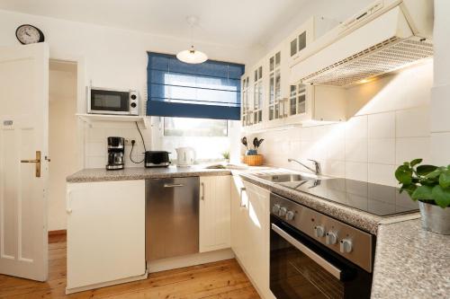 a kitchen with white cabinets and a stove top oven at Ferienhaus Seepferdchen in Fehmarn