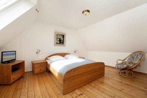 a bedroom with a bed and a tv on a wooden floor at Ferienhaus Seepferdchen in Fehmarn