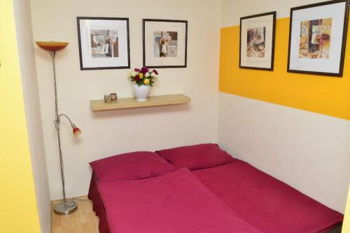 a red bed in a room with pictures on the wall at Penzion Čokoláda in Poděbrady