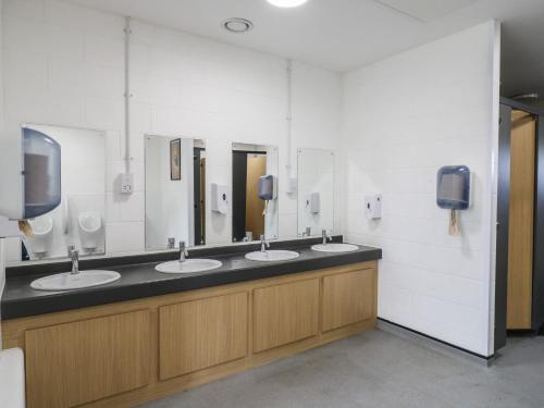 un baño con tres lavabos y tres espejos en Daisy Cow Shed 1, en Woodbridge