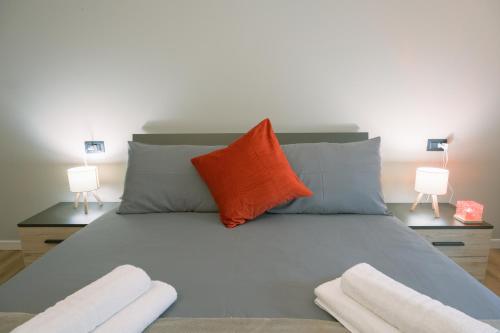 a bed with an orange pillow and two lamps at Costa Blu-Pool and Terrace overlooking the lake in Riva di Solto