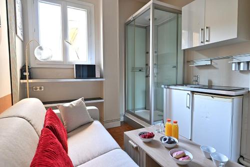 un salon avec un canapé et une cuisine dans l'établissement Petit studio pratique Neuilly-sur-Seine - II, à Neuilly-sur-Seine