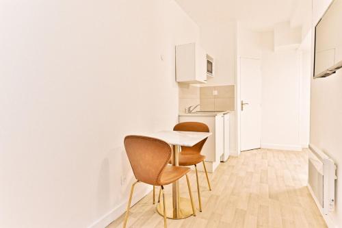 une cuisine avec une table et des chaises dans une pièce dans l'établissement Cozy and convenient studio in Asnières-sur-Seine-II, à Asnières-sur-Seine