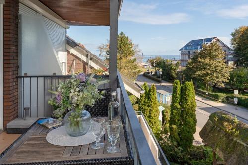 a table on a balcony with a vase of flowers at Haus Baltic Traumfabrik in Scharbeutz