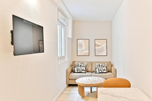 un salon avec un canapé et une télévision sur un mur dans l'établissement Cozy and convenient studio in Asnières-sur-Seine-II, à Asnières-sur-Seine