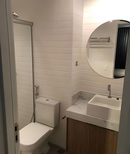 a bathroom with a toilet and a sink and a mirror at Excelente e confortável Flat in Goiânia