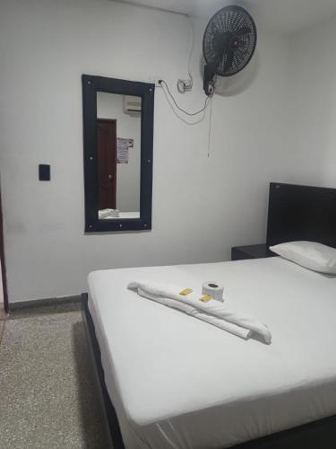 a room with a bed with a fan and a mirror at Hotel Los Arcangeles in Cúcuta