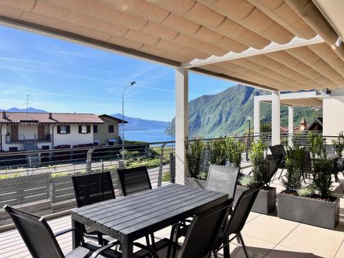 a table and chairs on a deck with a view of the mountains at Costa Blu-Pool and Terrace overlooking the lake in Riva di Solto