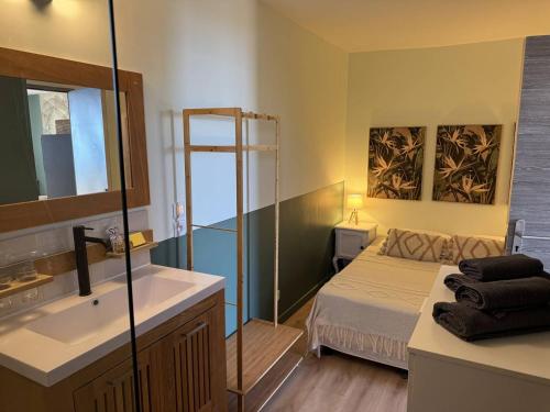 une salle de bain avec un lit, un lavabo et un miroir dans l'établissement Les Floralies à Saint-Clair, au Lavandou