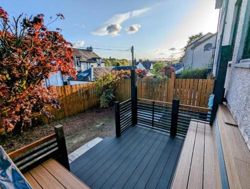 a wooden deck with two benches and a fence at 12 & 14 On the Hill Aberfoyle, twin holiday cottages in Scenic Loch Lomond & Trossachs National Park in Aberfoyle