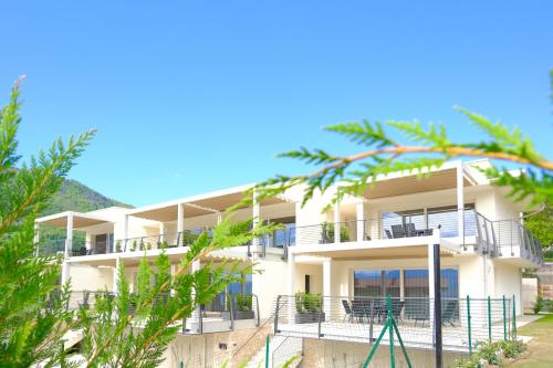 a white apartment building with balconies and trees at Costa Blu-Pool and Terrace overlooking the lake in Riva di Solto