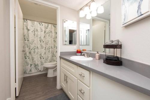 a bathroom with a sink and a toilet and a mirror at Snazzy 2 Bedroom Pad with Rooftop Pool and Hollywood Sign View in Los Angeles