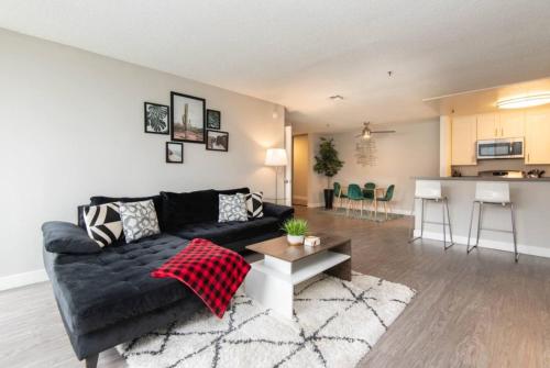 a living room with a black couch and a kitchen at Snazzy 2 Bedroom Pad with Rooftop Pool and Hollywood Sign View in Los Angeles
