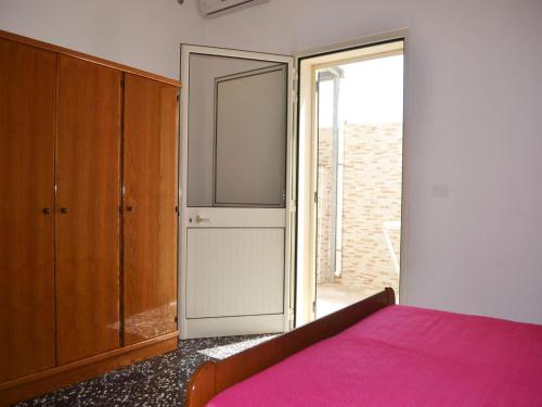 Schlafzimmer mit einem rosa Bett und einer Glasschiebetür in der Unterkunft Holiday home SORA with air conditioning in Torre dellOrso in Torre dell'Orso