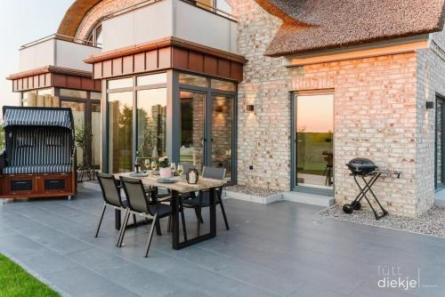 a patio with a table and chairs and a grill at Lütt Diekje in Westermarkelsdorf