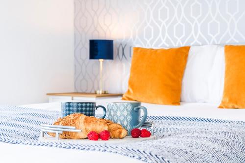 a tray with a croissant and strawberries on a bed at Redlands House By Urban Hideaways in Barry