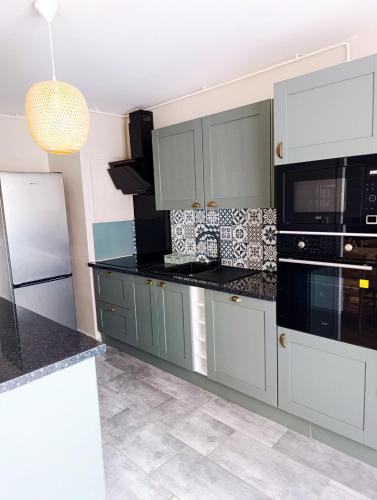 une cuisine avec des placards gris et des comptoirs noirs dans l'établissement Appartement 3 chambres à Sedan, à Sedan