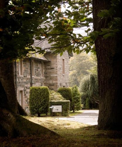 a stone house with a bench in front of it at Craigatin House & Courtyard in Pitlochry