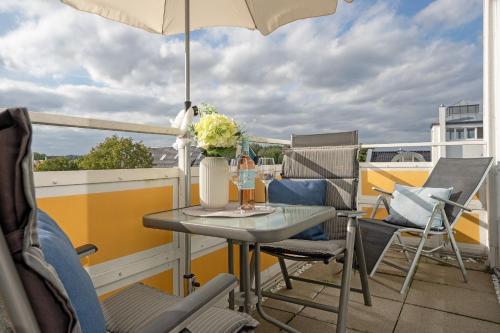 einen Tisch und Stühle auf einem Balkon mit Sonnenschirm in der Unterkunft Strandhotel Scharbeutz Dünenliebe in Scharbeutz