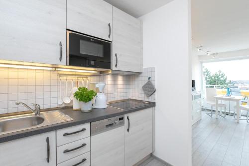 eine Küche mit weißen Schränken und einer Spüle in der Unterkunft Strandhotel Scharbeutz Dünenliebe in Scharbeutz