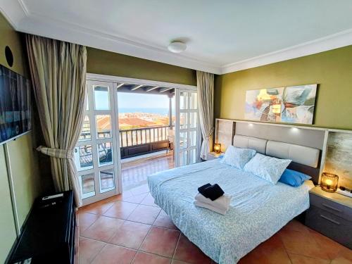a bedroom with a large bed and a balcony at Villa Magnificent 5-star with sea view, jacuzzi and pool in Arguineguín