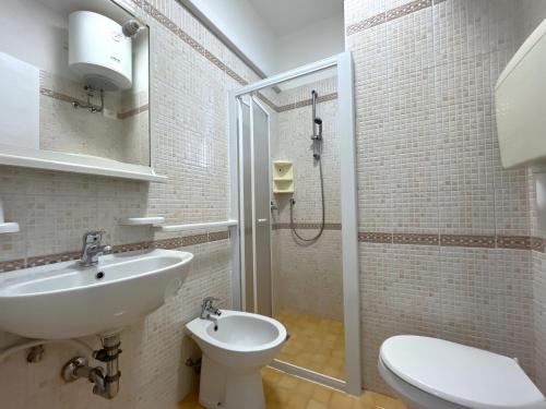 Un baño con lavabo, inodoro y ducha. en Corso - Appartamenti, en Bibione