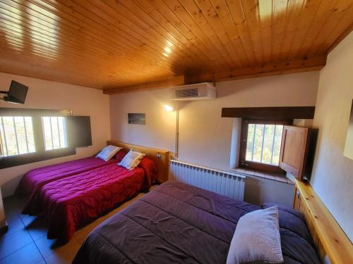 a bedroom with two beds and a wooden ceiling at Cal Sicull in Santa María de Marlés