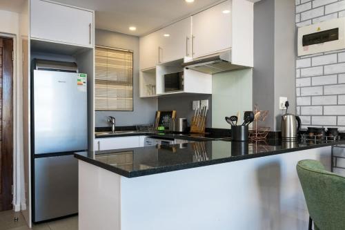 a kitchen with white cabinets and a black counter top at Stylish Gem in East Point 19 in Durban