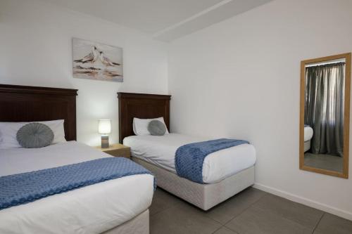 a hotel room with two beds and a mirror at Stylish Gem in East Point 19 in Durban