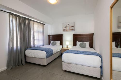 a hotel room with two beds and a mirror at Stylish Gem in East Point 19 in Durban