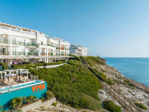 a building on a cliff next to the ocean at VIVA Cala Mesquida Resort & Spa in Cala Mesquida
