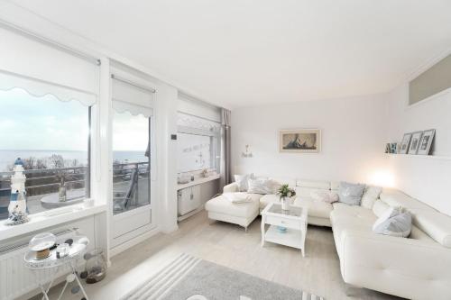 een woonkamer met witte meubels en een groot raam bij Strandappartements am Leuchtturmweg Baltic-View in Kellenhusen