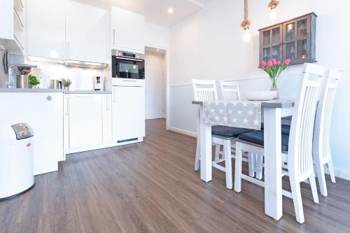 沙博伊茨Haus Meeresstrand Gestrandet的厨房配有白色橱柜和桌子及椅子