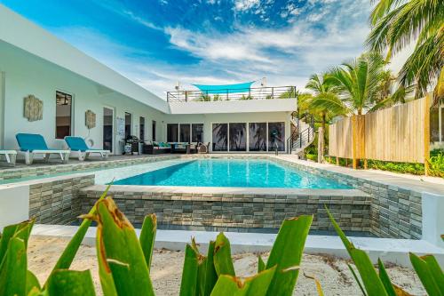a pool in the backyard of a house with palm trees at Belize Oceanfront Villa W Pool, Beach & Pier in Basil Jones