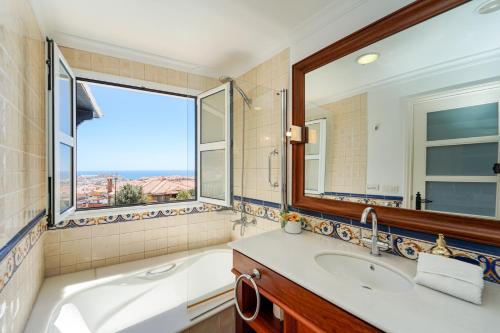 a bathroom with a tub and a sink and a window at Villa Magnificent 5-star with sea view, jacuzzi and pool in Arguineguín