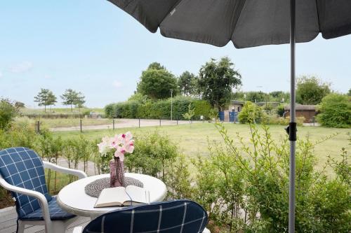 a table with a vase of flowers and an umbrella at Blankwasserweg 131 Lensterstrand Oase Bungalow 5 in Lenste