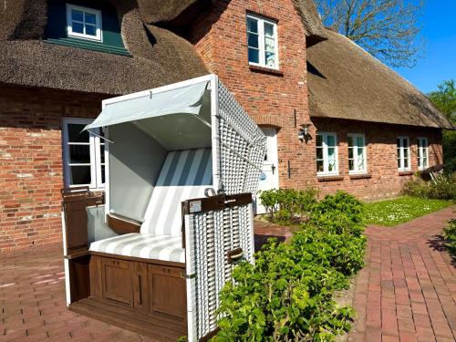 an outdoor bench in front of a thatched house at Reetkehlchen in Alkersum