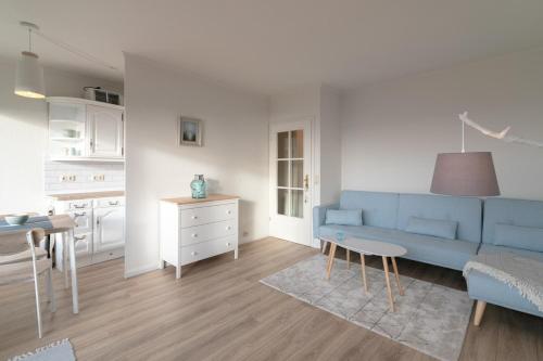a living room with a blue couch and a kitchen at Strandidyll- Wohnung 41 in Grömitz