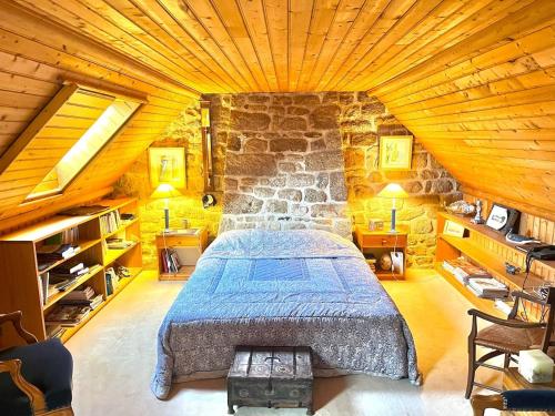 une chambre avec un lit et un mur en pierre dans l'établissement Maison de Famille Pen Morvan, à Combrit