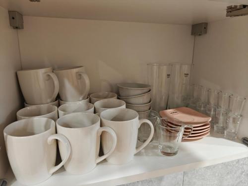 a shelf with white cups and plates on it at Portki - Cztery Pory Roku in Pszczeliny
